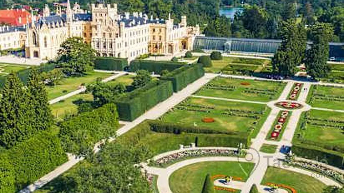 Summer view of Lednice Castle & Park in the Czech Republic featuring the UNESCO-listed Neo-Gothic palace, landscaped gardens, peaceful lakes, the historic Minaret, and lush green parkland.