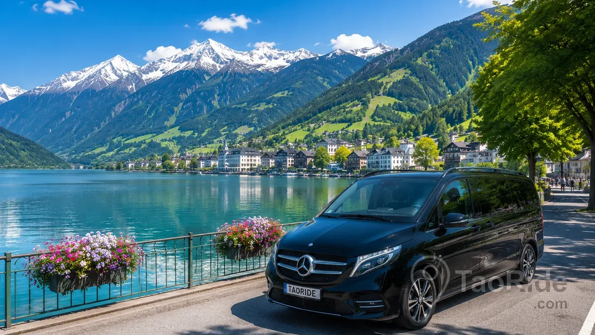 Luxury Mercedes private transfer beside Lake Zell in Zell am See, Austria, surrounded by crystal-clear Alpine waters, snow-capped mountains, lakeside promenade, and breathtaking summer scenery.