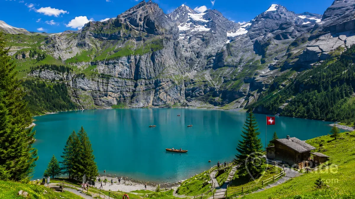 Panoramic view of Oeschinen Lake (Oeschinensee) in the Swiss Alps, featuring crystal-clear turquoise water, dramatic mountain peaks, rowing boats, and breathtaking scenery near Kandersteg, Switzerland.
